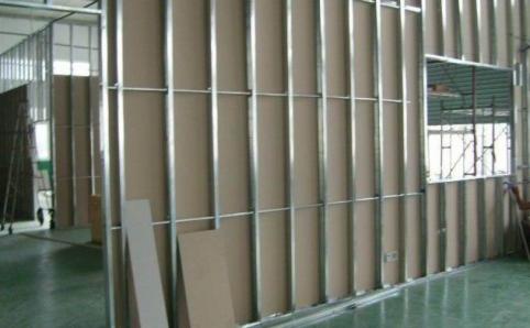 Konstrukcja ścian działowych z profili stalowych i płyt karton-gips, widoczne profile pionowe i poziome, otwór okienny w ścianie po prawej stronie, surowy stan wykończenia wnętrza.