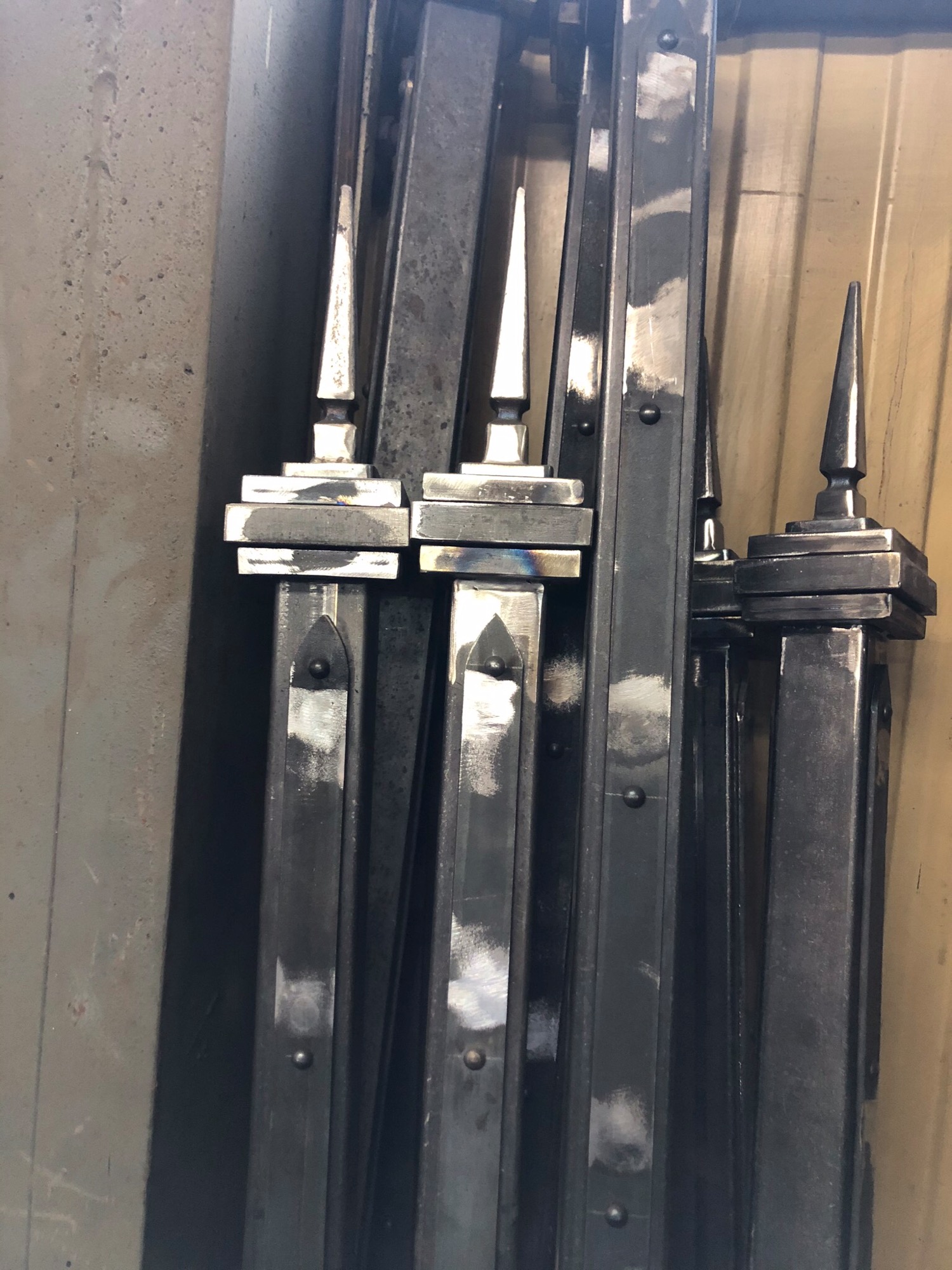 Metalowe elementy ogrodzenia z ostrymi zakończeniami, po obróbce, widoczne ślady spawania i szlifowania.