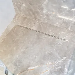 Wykończona kabina prysznicowa z odpływem liniowym i płytkami imitującymi marmur w odcieniach szarości i beżu, widok z góry.