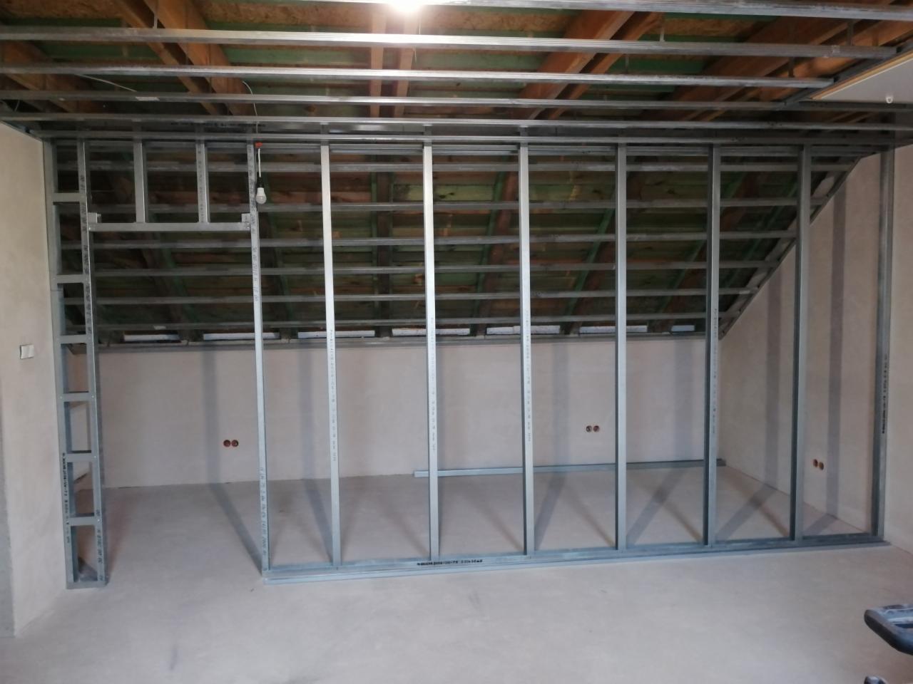 Metalowy szkielet konstrukcji ścianki działowej w poddaszu, widoczne profile pionowe i poziome, surowy stan przed obłożeniem płytami.