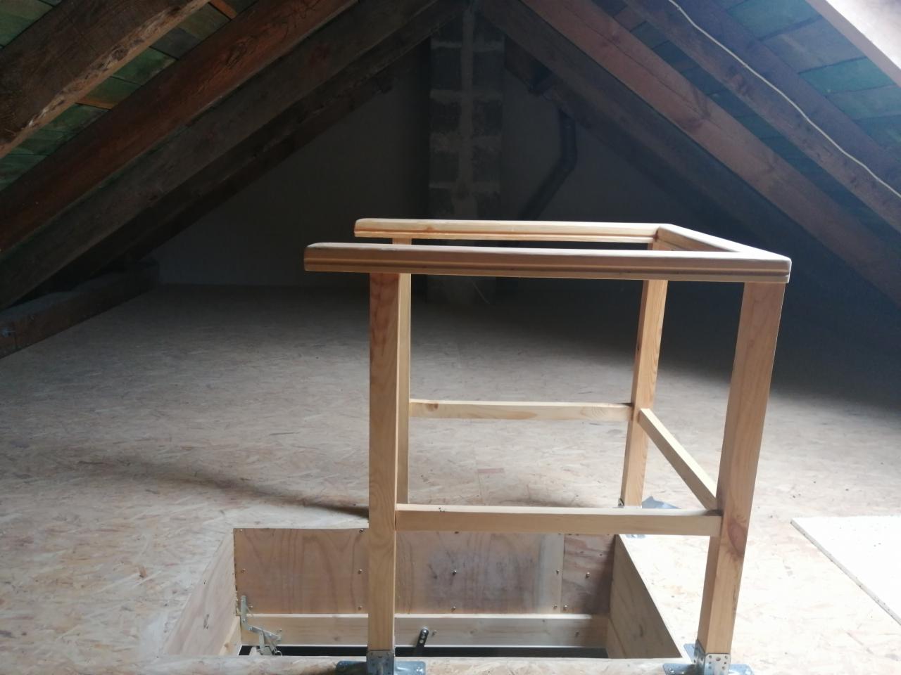 Drewniana konstrukcja zabezpieczająca otwór w podłodze na poddaszu, widoczne krokwie dachowe i płyta OSB.