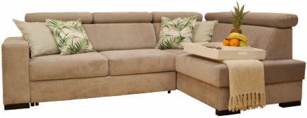 Beżowy narożnik z poduszkami w tropikalne liście i tacą z owocami, na tle jasnej ściany.