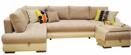 Beżowy narożnik z poduszkami w odcieniach beżu i żółci, z wysuwaną szufladą w podstawie i tacą z owocami na boku.