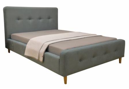 Szare, tapicerowane łóżko z zagłówkiem z guzikami, na drewnianych nóżkach, z beżową pościelą i kremowym pledem, na białym tle.