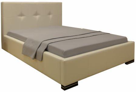 Beżowe łóżko tapicerowane z pikowanym zagłówkiem i szarą pościelą oraz pledem, widoczne czarne nóżki.