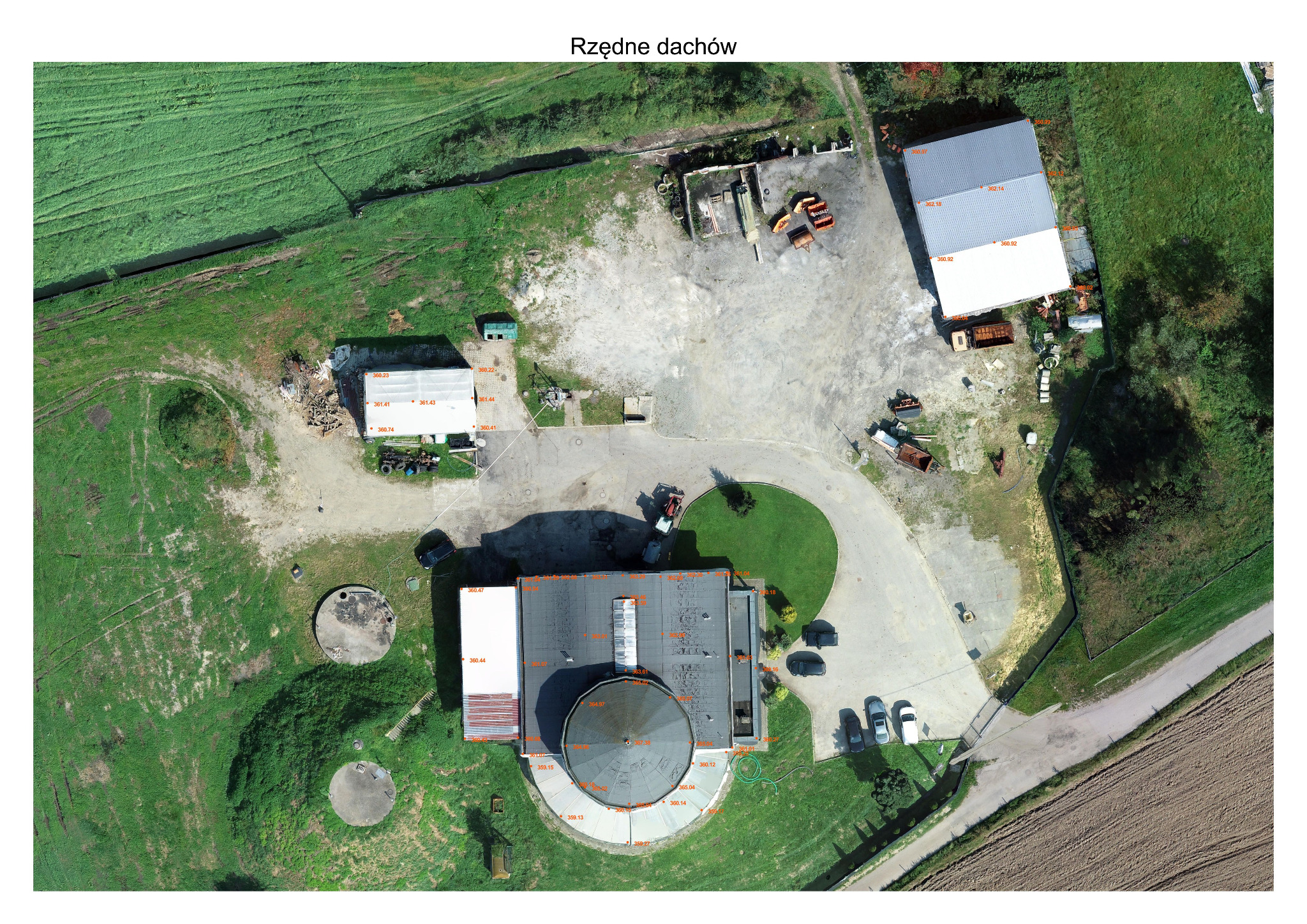 Zdjęcie z drona przedstawia budynek z płaskim dachem i okrągłą nadbudówką, otoczony trawnikiem, parkingiem z samochodami i polami uprawnymi. Na dachu i w otoczeniu budynku widoczne są numeryczne...