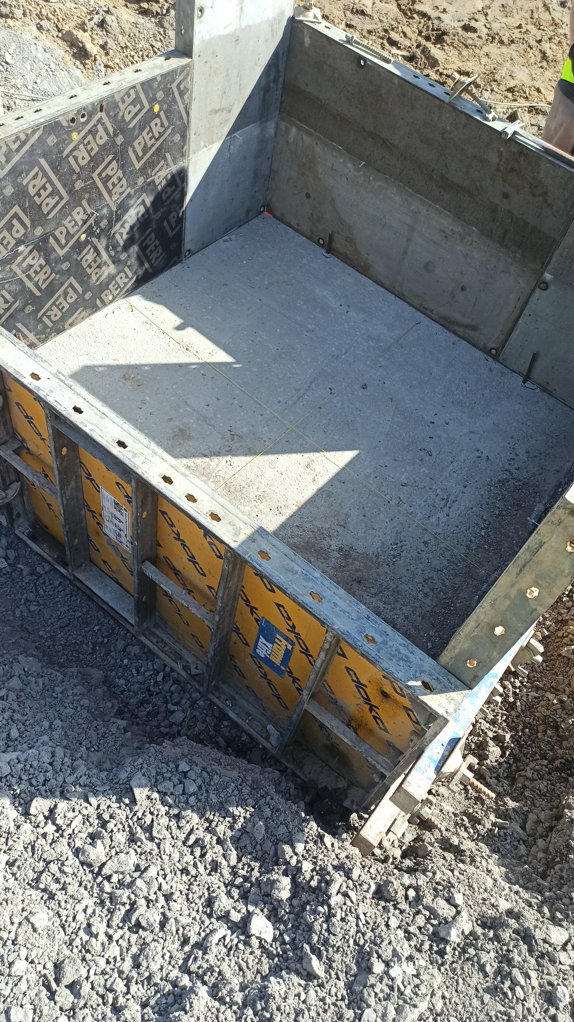 Wykonany wykop z betonowym dnem i zabezpieczeniem ścian szalunkami Peri i Doka, widoczne ślady po sznurkach geodezyjnych.