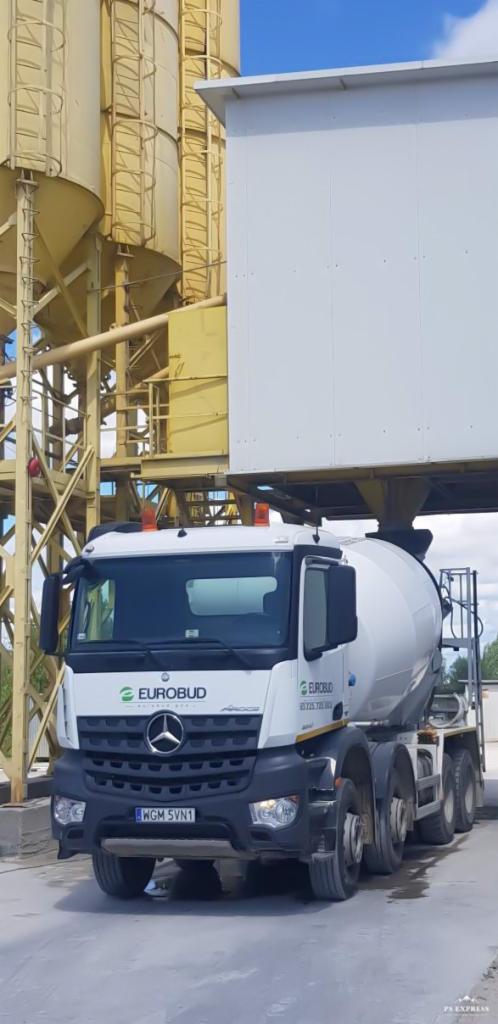Ciężarówka z betonomieszarką marki Mercedes-Benz Eurobud pod silosami na terenie zakładu.