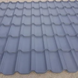 Szare metalowe dachówki modułowe w regularnym wzorze, widoczne z bliska, z delikatnym cieniowaniem podkreślającym kształt.