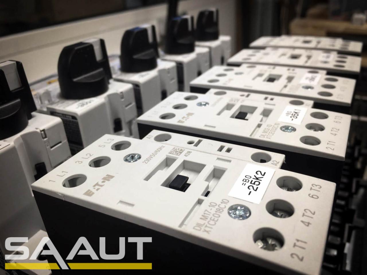 Szereg styczników elektrycznych Eaton DIL M17-10 i DIL M32-10 z czarnymi pokrętłami, widoczne numery seryjne i oznaczenia na obudowach, ułożone na szynie DIN.