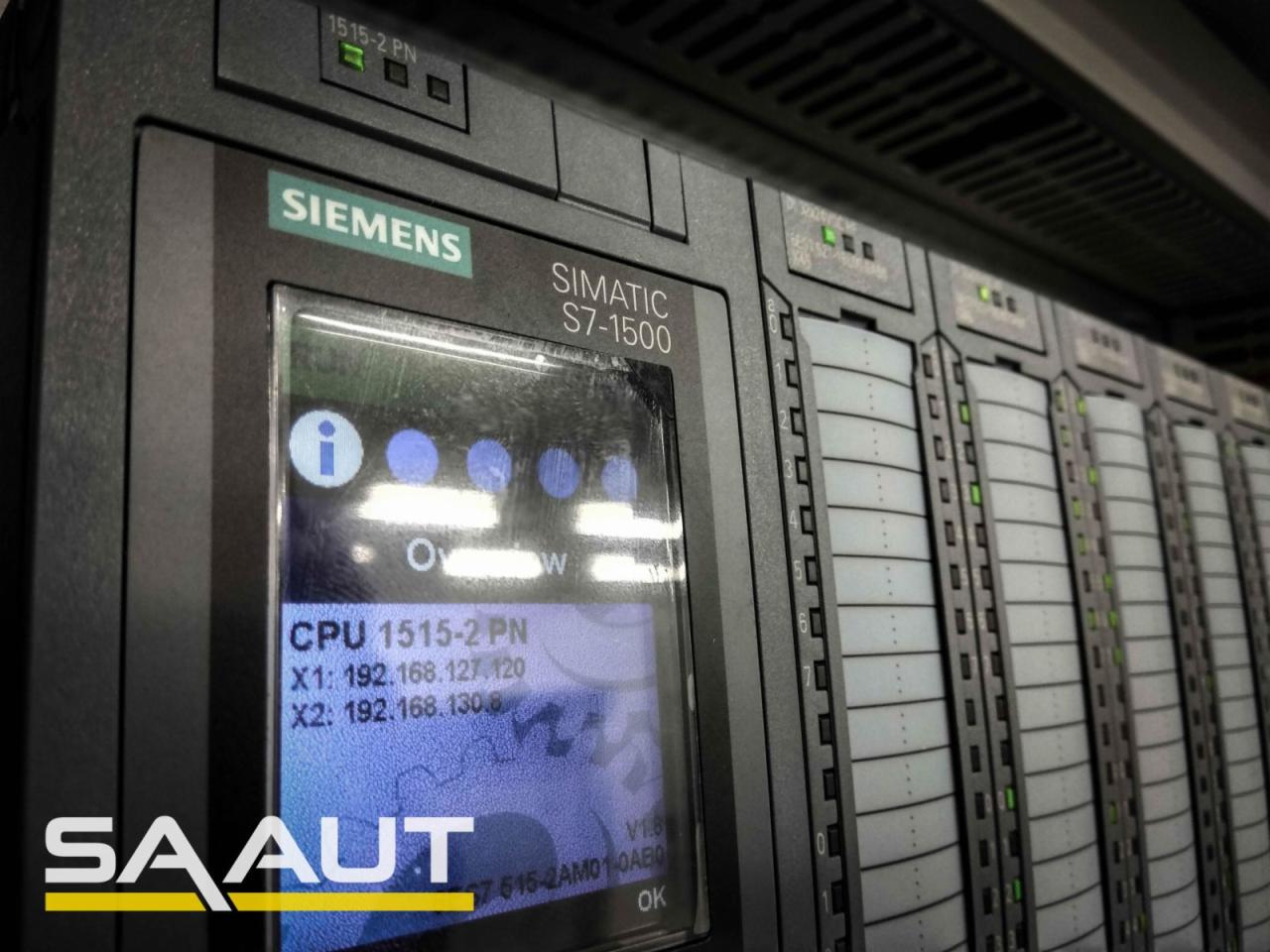 Panel sterowania Siemens Simatic S7-1500 z widocznym ekranem wyświetlającym informacje o CPU 1515-2 PN oraz adresy IP, obok szereg modułów z diodami LED.