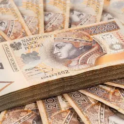 Stos banknotów dwustuzłotowych na tle rozłożonych banknotów, widoczny portret króla Zygmunta I Starego.