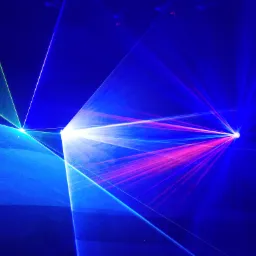 Wiązki różnokolorowych laserów (zielone, niebieskie i różowe) przecinają ciemną przestrzeń, tworząc dynamiczny efekt wizualny.