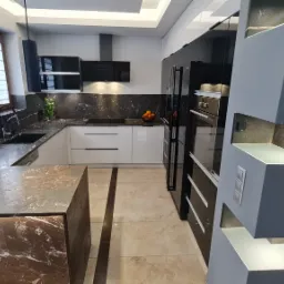 Nowoczesna kuchnia z marmurowym blatem, czarnym zlewem i bukietem tulipanów w wazonie, oświetlona wiszącymi lampami i podświetleniem szafek.