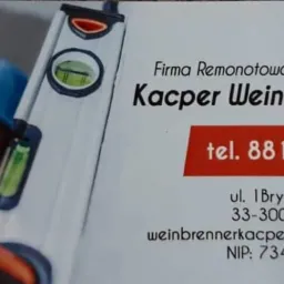 Wizytówka firmy remontowo-budowlanej Kacper Weinbrenner, obok której widoczny jest fragment pracownika w kasku i poziomica.