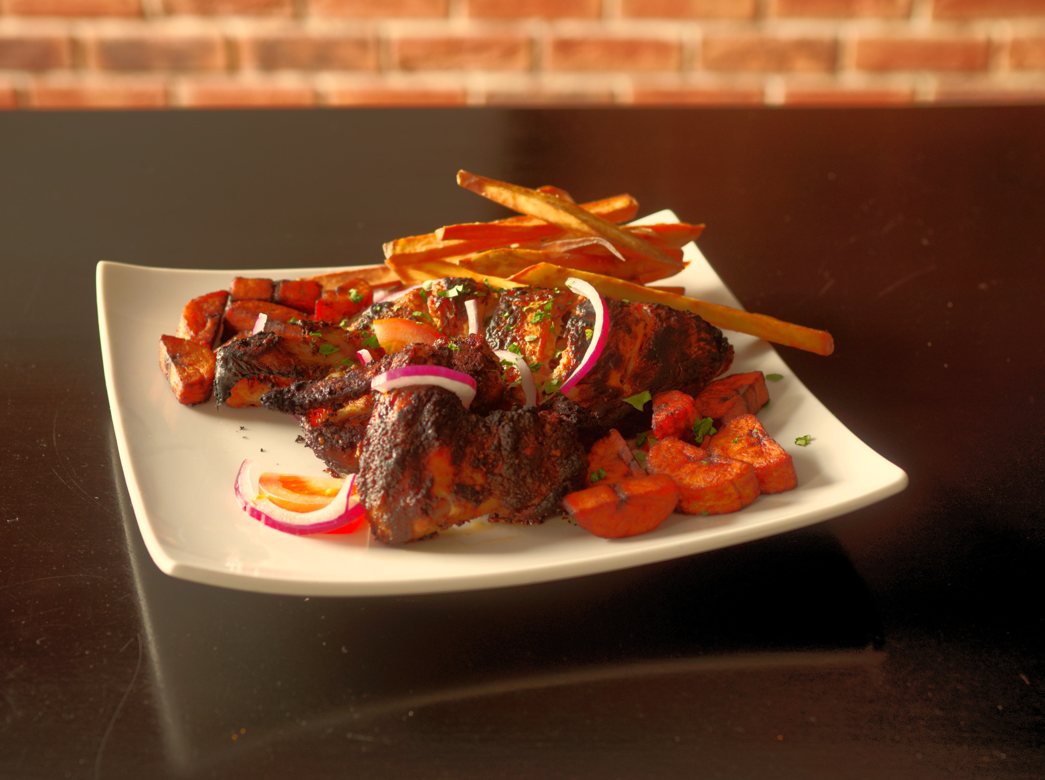 Apetyczna kompozycja grillowanego mięsa, smażonych batatów i chrupiących frytek z batatów, udekorowana krążkami czerwonej cebuli i posiekaną natką pietruszki, prezentowana na białym, kwadratowym...