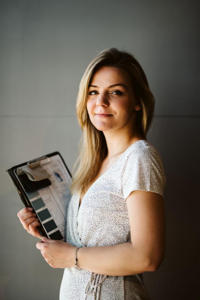 Projektantka wnętrz z Gdyni prezentuje paletę kolorów i próbkę materiału na desce z planem pomieszczenia.