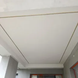 Wykończony sufit podwieszany z listwami LED w nowym budynku. Świeżo położona gładź szpachlowa na suficie. Widoczne zabezpieczone okna folią malarską.