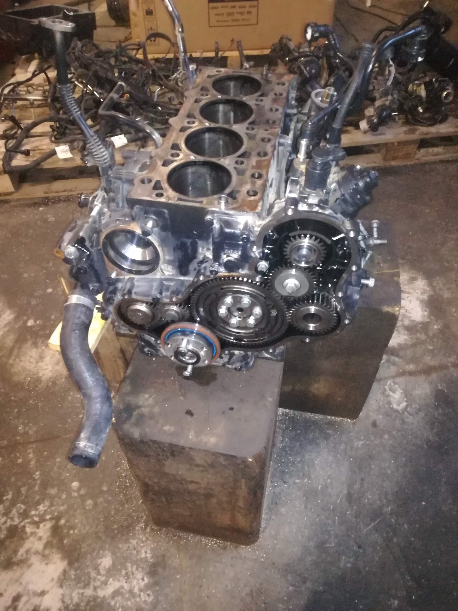 Silnik samochodowy z odsłoniętymi cylindrami i przekładnią zębatą, umieszczony na metalowym stojaku w warsztacie.