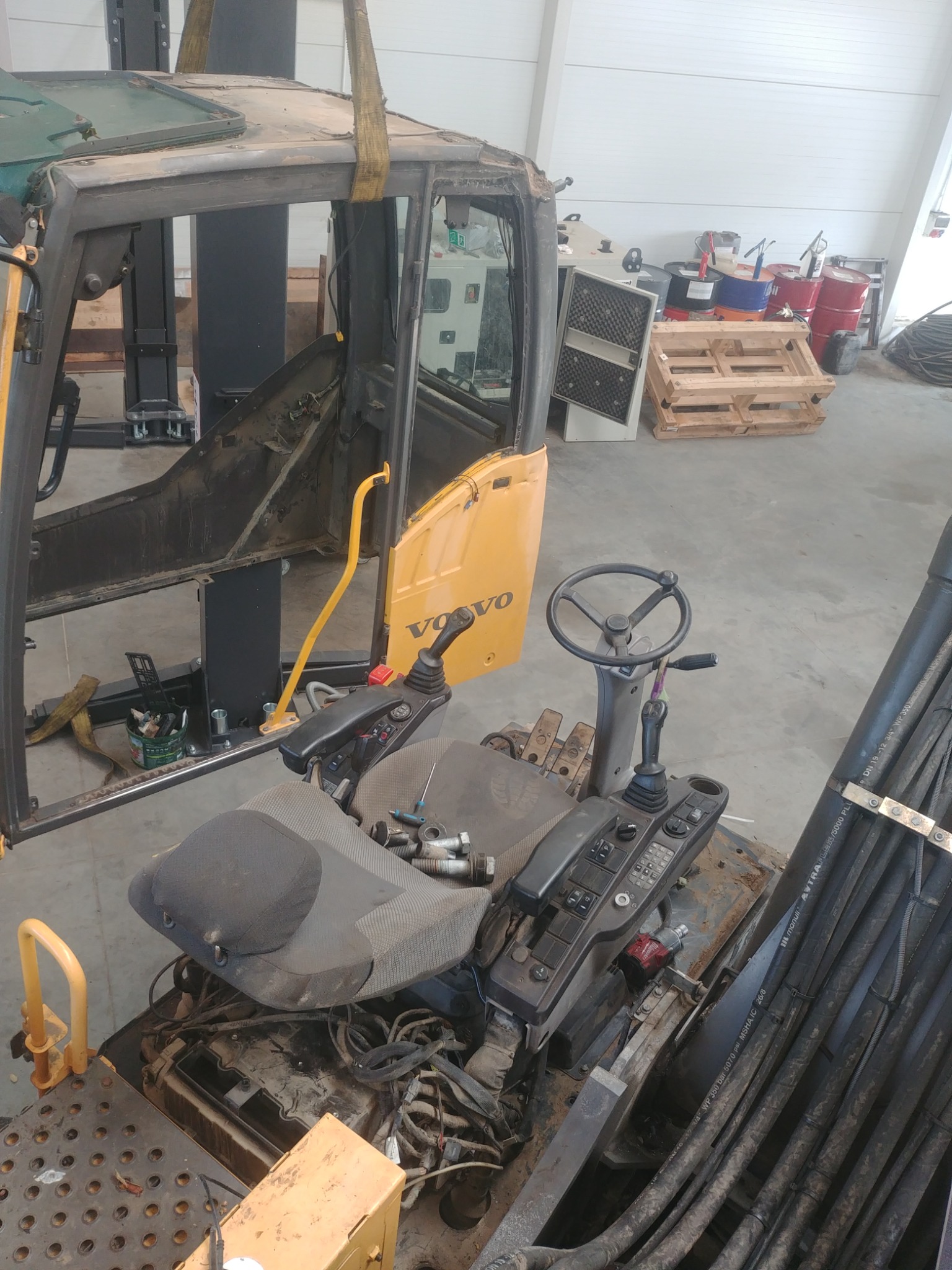 Kabina maszyny budowlanej Volvo w trakcie demontażu lub naprawy, widoczne narzędzia i elementy sterowania, w tle warsztat.