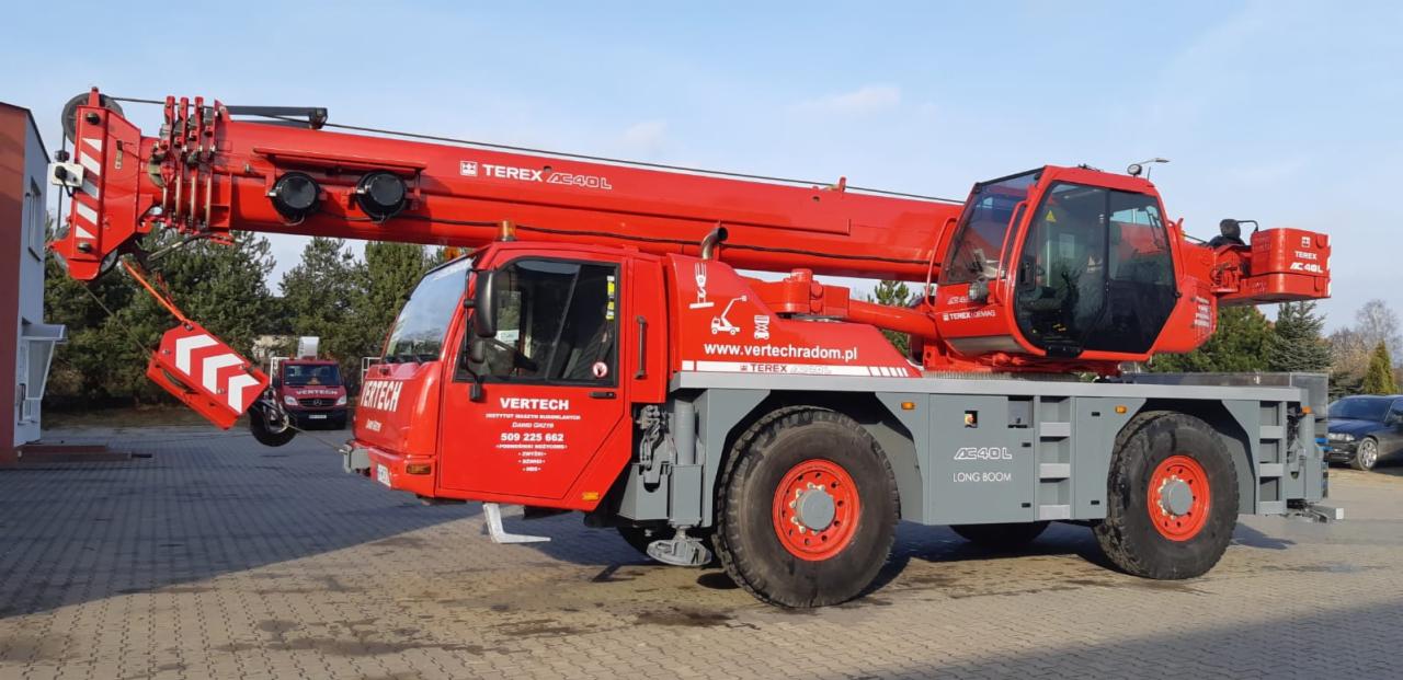 Czerwony dźwig samojezdny Terex AC40L z wysuniętym ramieniem, zaparkowany na placu firmy Vertech z widocznym logo i numerem telefonu.
