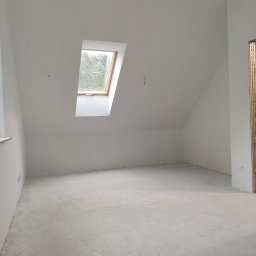 OPTYplus BUD Sp. z o.o. - Poddasze z wylaną, surową wylewką, widok na okno dachowe i przygotowane ściany do dalszych prac wykończeniowych.