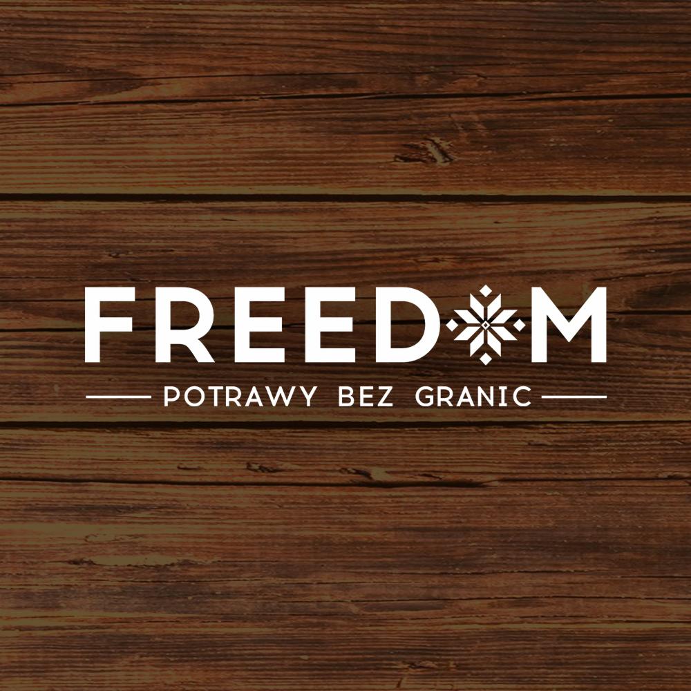 Logo firmy cateringowej 'FREEDOM - potrawy bez granic' na tle drewnianej powierzchni, śnieżynka zamiast litery O w nazwie.