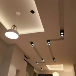 Sufit podwieszany z oświetleniem punktowym i wiszącą lampą w nowoczesnym salonie, widok z dołu.