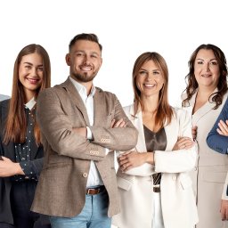 TOBIS Nieruchomości - Zespół agentów nieruchomości uśmiecha się, stojąc ramię w ramię na białym tle. Różnorodne stylizacje biznesowe, od brązowych marynarek po eleganckie garsonki.