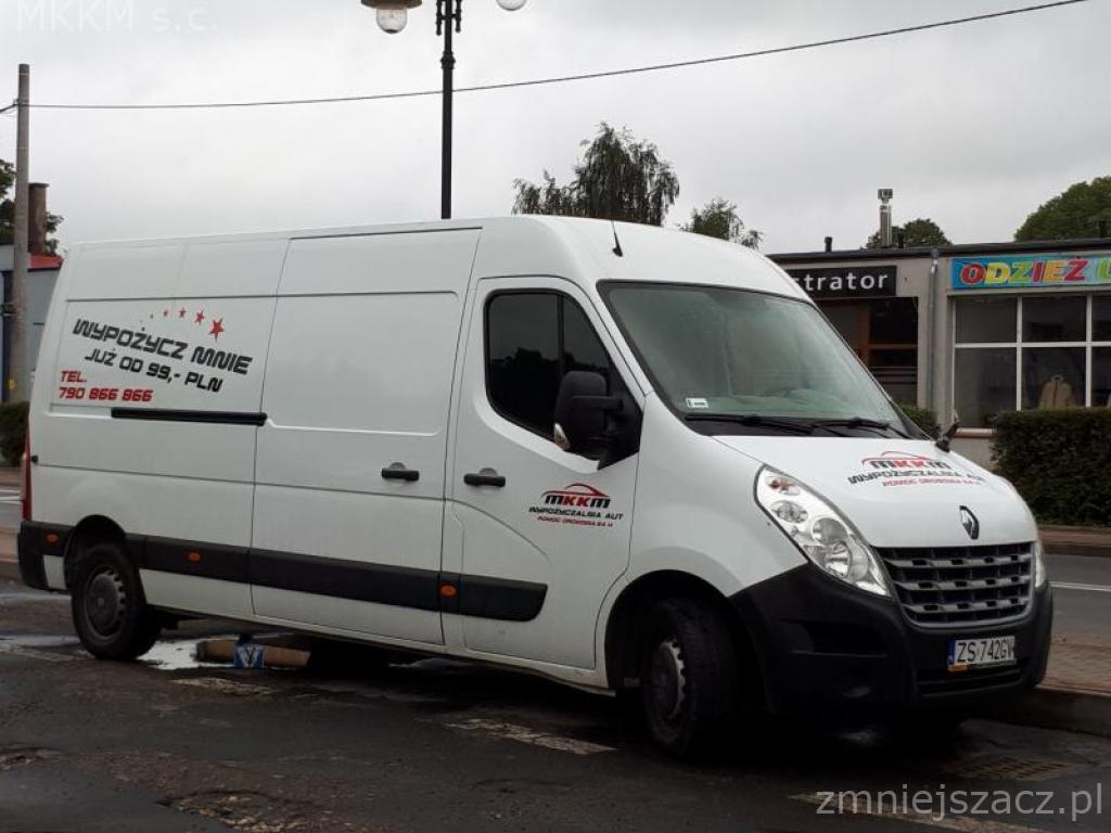 Biały bus Renault Master z naklejkami reklamowymi firmy MKKM s.c. oferującej wynajem, zaparkowany na ulicy. Na boku pojazdu widnieje napis 'WYPOŻYCZ MNIE JUŻ OD 99,- PLN' wraz z numerem telefonu.