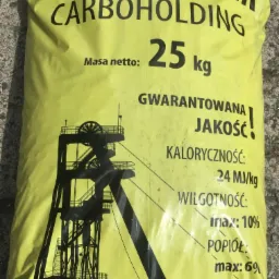 Żółty worek z nadrukiem nazwy 'EKOGROSZEK CARBOHOLDING' i parametrami technicznymi, takimi jak kaloryczność, wilgotność i zawartość popiołu, na szarym, betonowym podłożu.