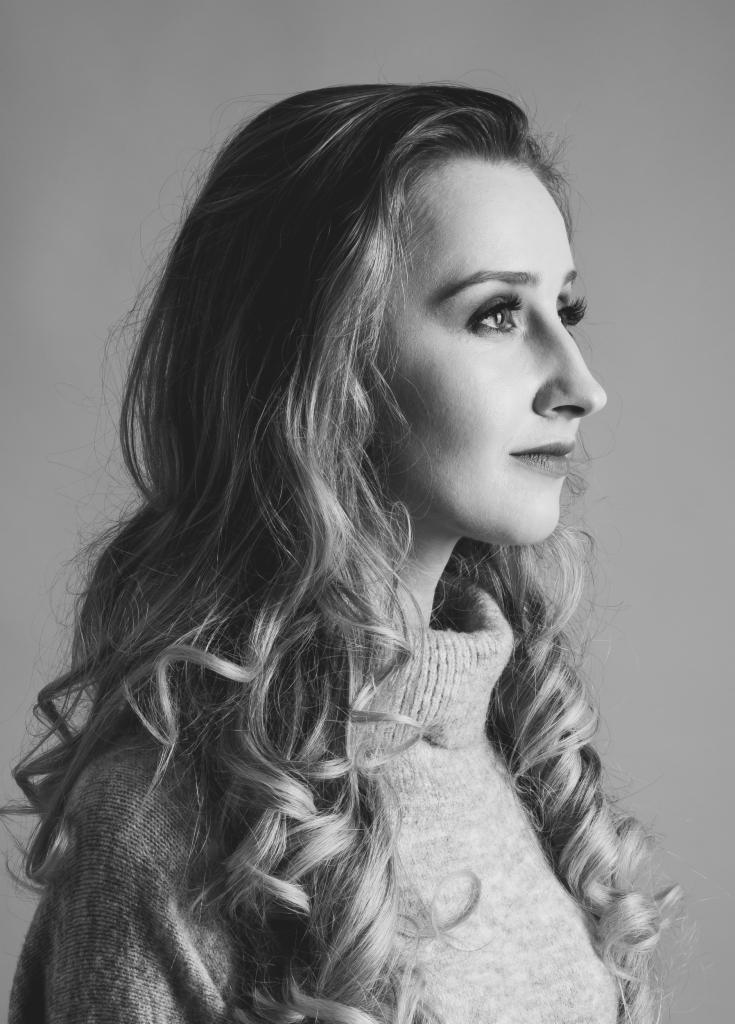 Portret profilowy kobiety z długimi, kręconymi włosami w Lublinie, wykonany w czerni i bieli, z widocznym swetrem z golfem.