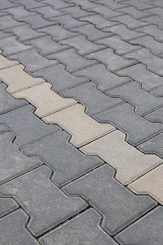 Ułożona kostka brukowa typu 'I', szara i beżowa, tworząca wzór diagonalny.