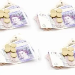 Cztery stosy banknotów 20 i 10 funtowych oraz monet ułożone na białym tle