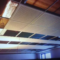 Montaż sufitu podwieszanego z płyt perforowanych w biurze, widoczne otwarte przestrzenie i instalacje nad sufitem.