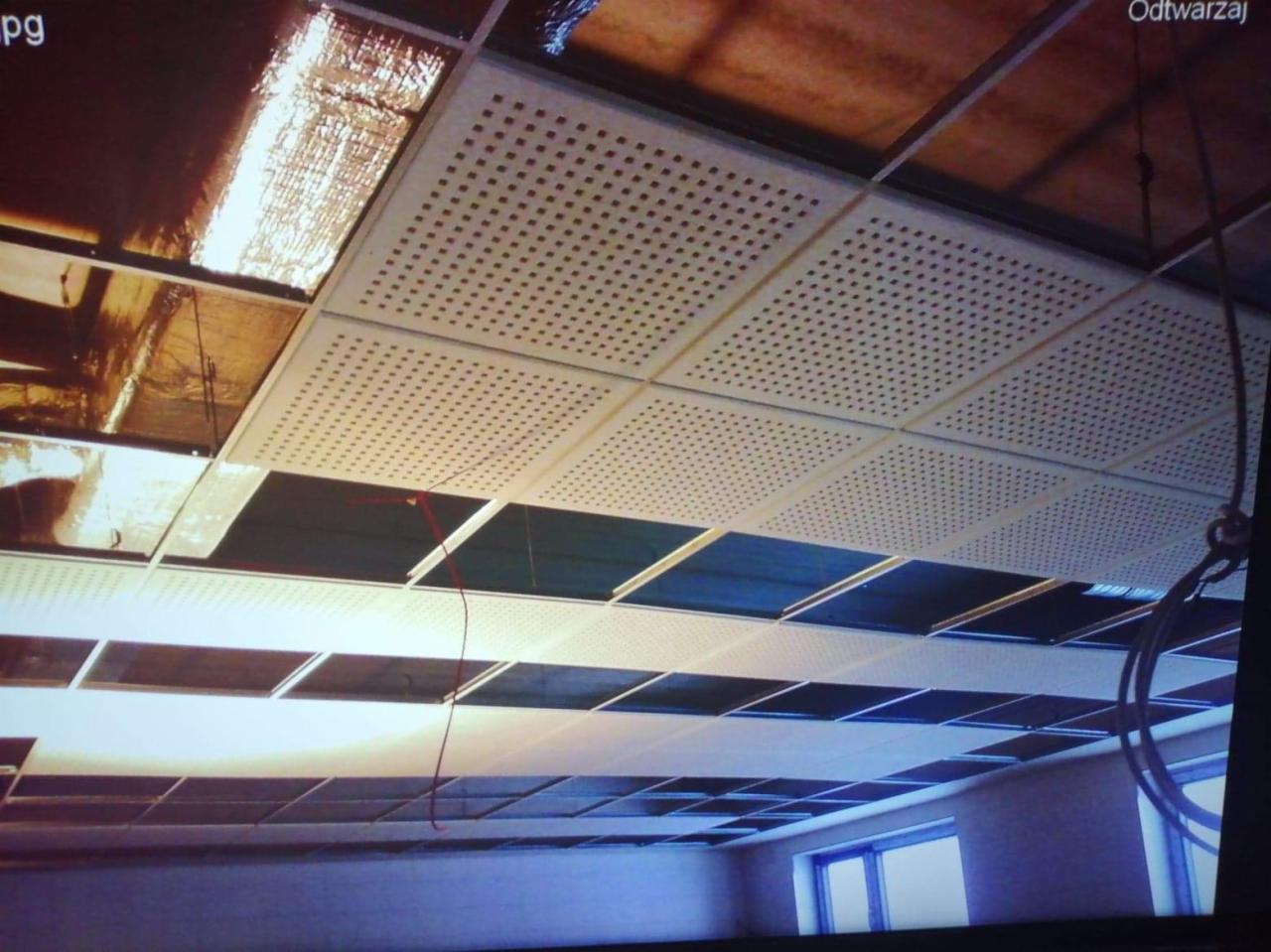 Montaż sufitu podwieszanego z płyt perforowanych w biurze, widoczne otwarte przestrzenie i instalacje nad sufitem.