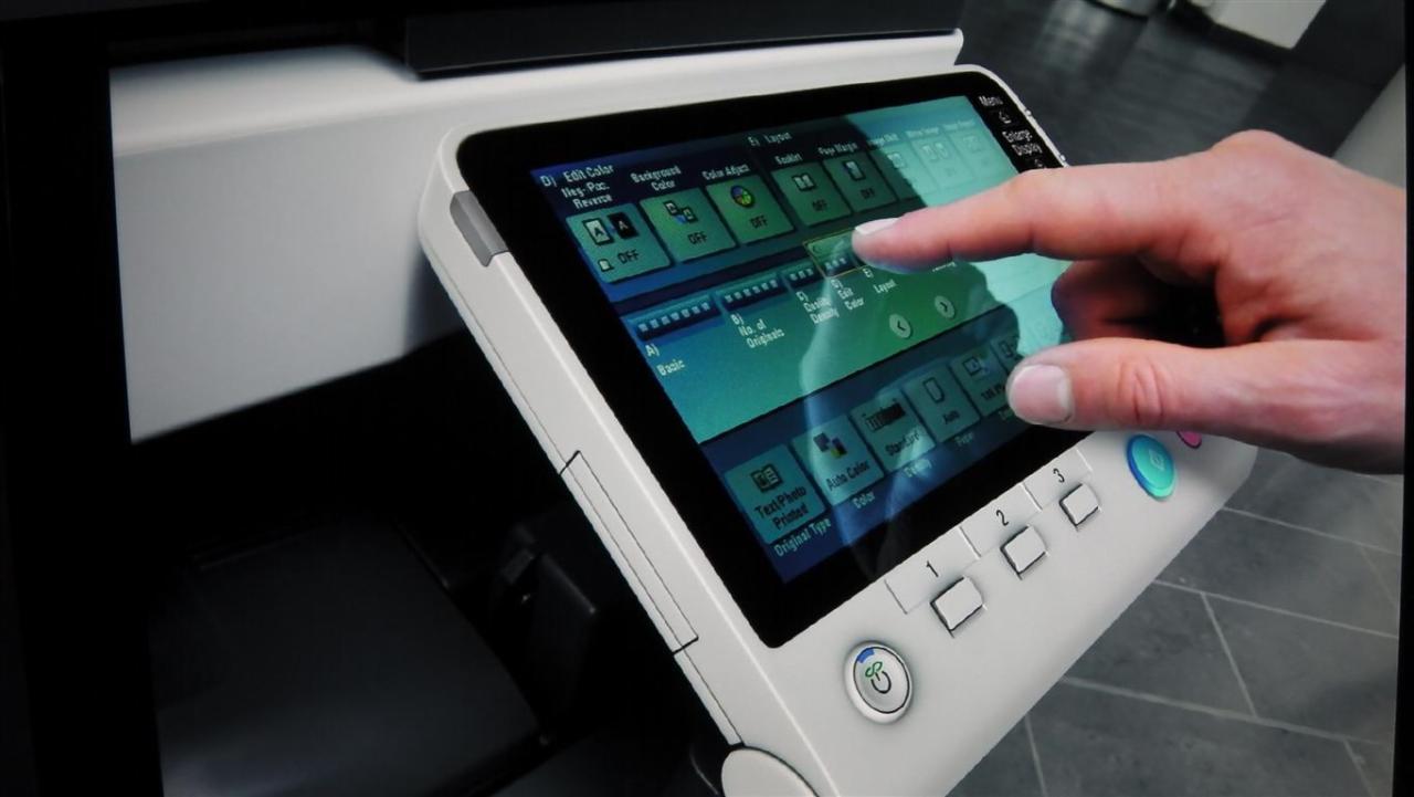 Palec wskazujący na panel dotykowy nowoczesnej kserokopiarki, aktywujący opcje edycji koloru i układu.