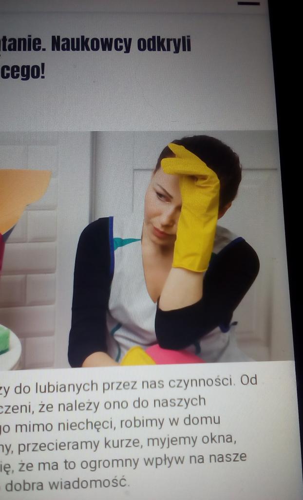 Zamyślona kobieta w fartuchu i żółtych rękawicach opiera głowę na dłoni, z widocznymi środkami czystości w tle, sugerując zmęczenie po sprzątaniu.