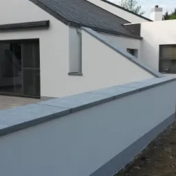 Nowoczesny dom z białą elewacją i szarymi elementami wykończeniowymi, widok na taras i ogród z ziemią.