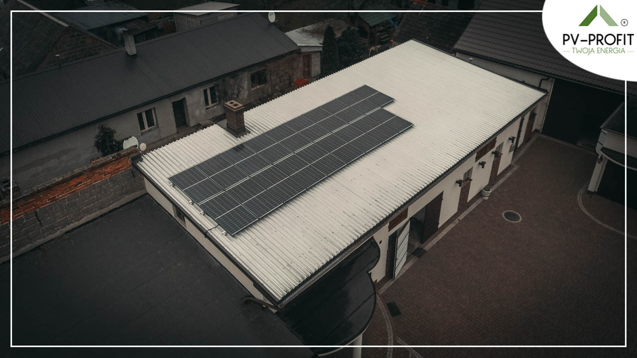 Widok z góry na budynek z panelami słonecznymi na dachu z blachy falistej; logo firmy PV-PROFIT w prawym górnym rogu.