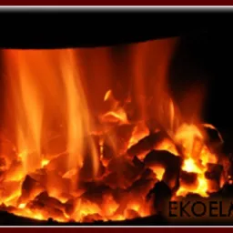 Płonące, rozżarzone bryły paliwa w palenisku, widoczne języki ognia i żarzące się fragmenty, ciemne tło.