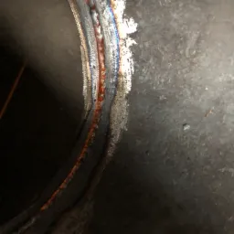 Spoina na metalowej rurze, widoczne przebarwienia termiczne i drobne odpryski.