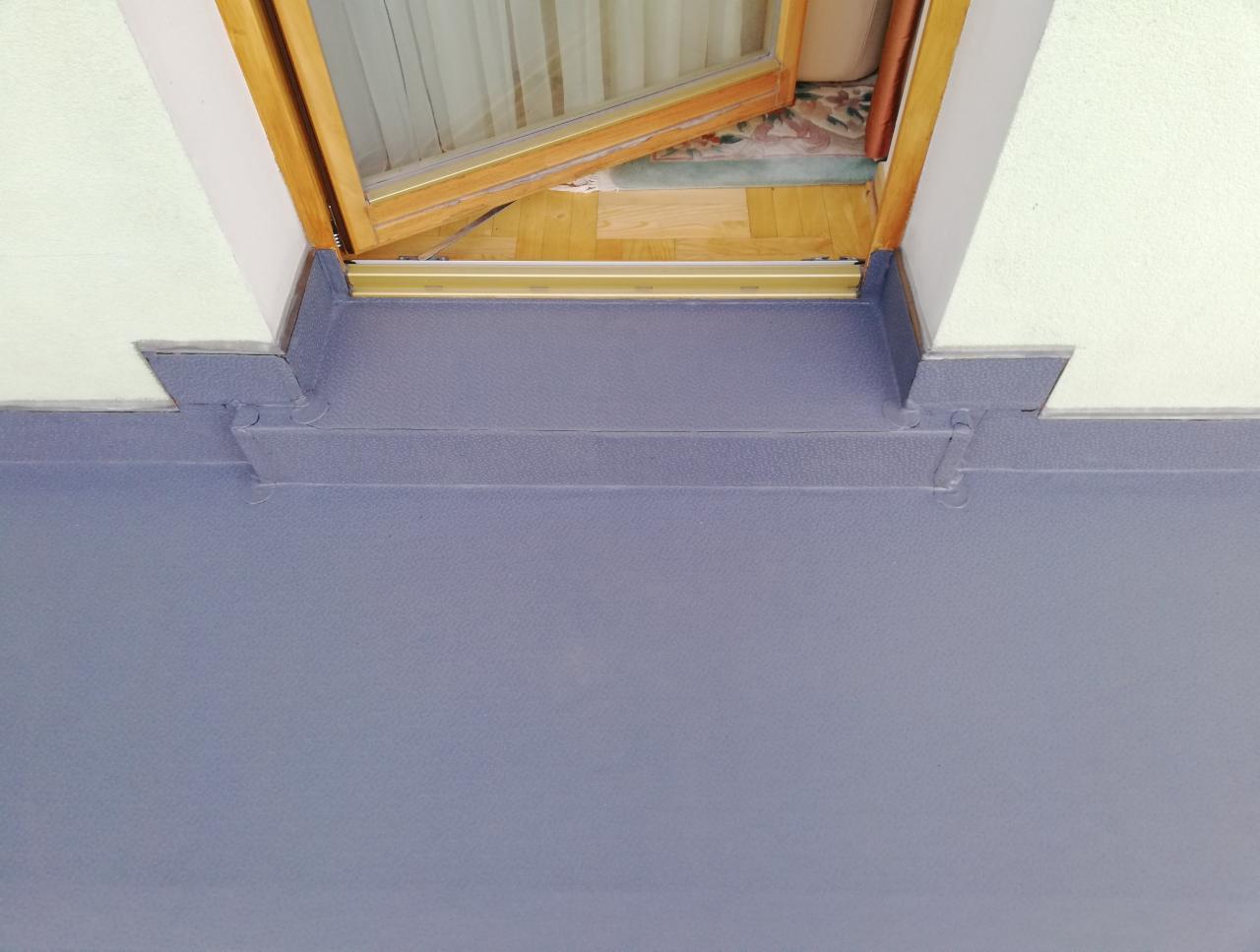 Szczegółowe ujęcie izolacji przeciwwodnej balkonu w Warszawie, widoczne łączenia i wykończenie przy progu drzwi balkonowych.