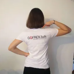 Kobieta w białej koszulce z nadrukowanym logo GOFREX.com (Bubble Waffle Makers & Accesories) na plecach, wskazująca na nie palcem.