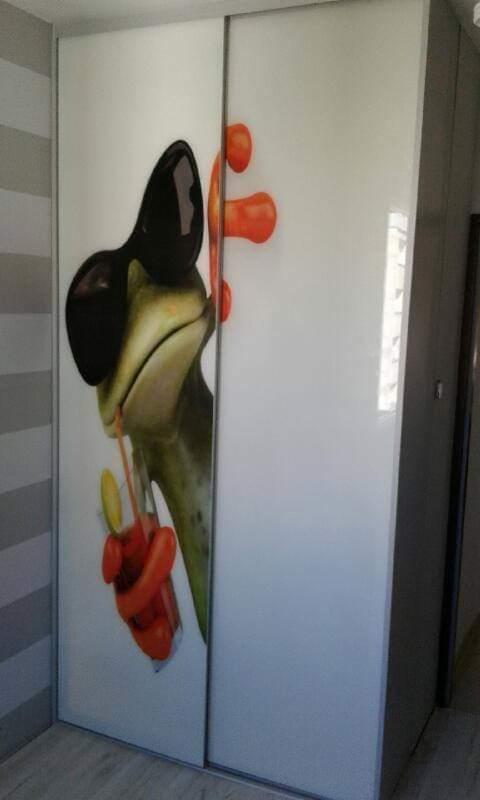 Szafa przesuwna z białymi frontami ozdobiona dużym, humorystycznym nadrukiem żaby w okularach pijącej drinka, wykonana na wymiar w Konstantynowie Łódzkim.