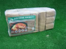 Paczka brykietu drzewnego w przezroczystej folii z etykietą, leżąca na sztucznej, zielonej trawie.