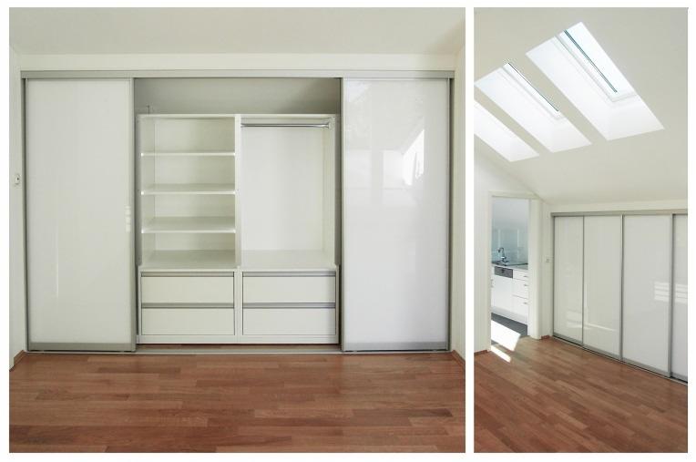 Biała zabudowa garderoby z przesuwnymi drzwiami i półkami, widok na poddasze z oknami dachowymi, drewniana podłoga.