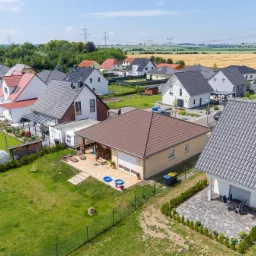 Panorama osiedla domów jednorodzinnych z widokiem z lotu ptaka, ukazująca różnorodność architektoniczną i zagospodarowanie przestrzeni.
