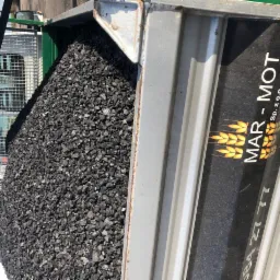 Wnętrze skrzyni ładunkowej wypełnione czarnym węglem kamiennym, widoczny fragment kabiny pojazdu oraz logo firmy MAR-MOT Sp. z o.o.