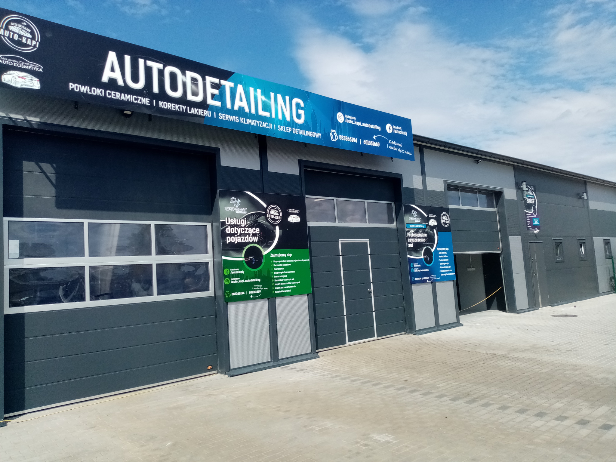 Budynek firmy oferującej auto detailing, z widocznym szyldem i reklamami usług, w tym powłok ceramicznych i korekty lakieru.